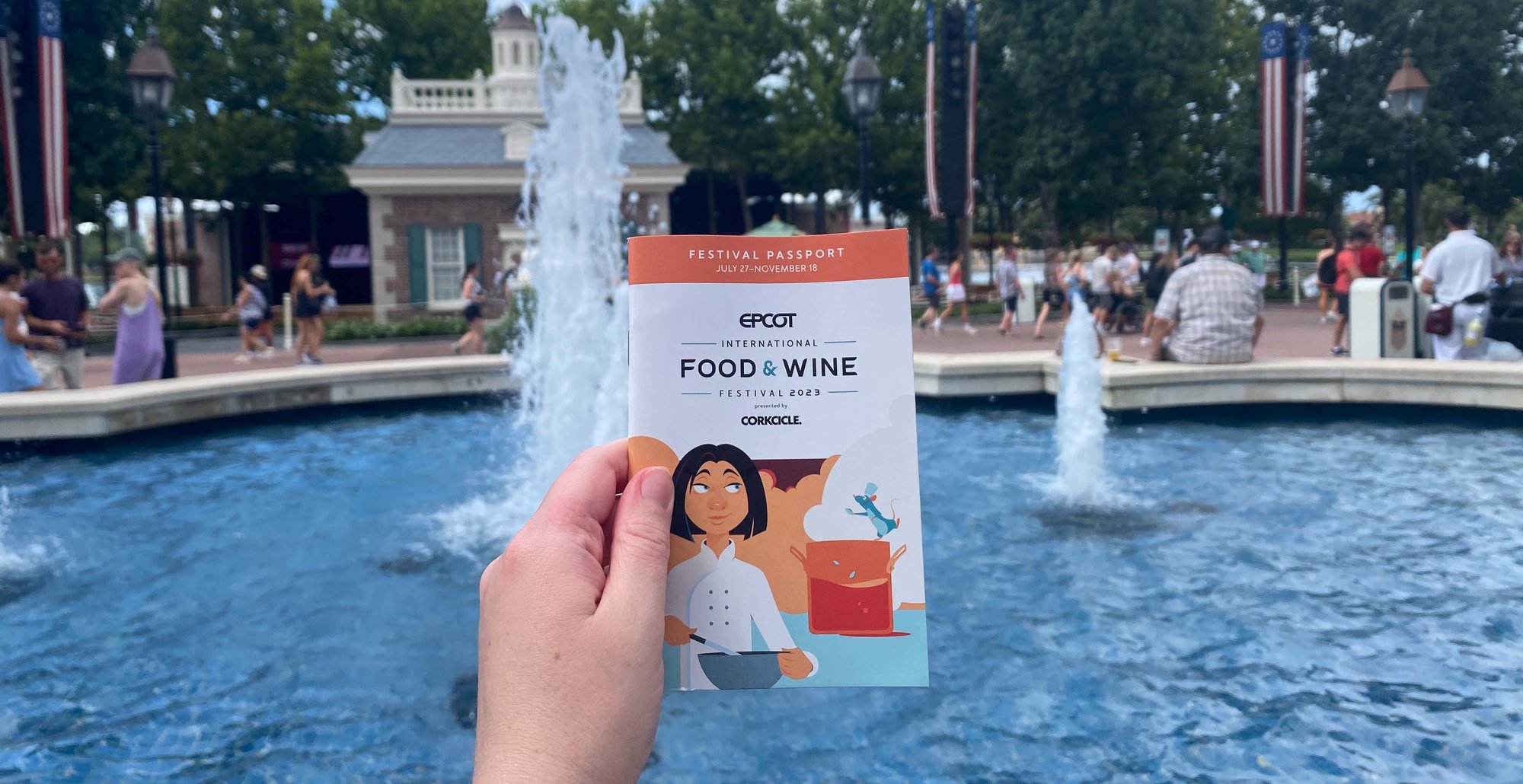 food and wine passport held up over a fountain